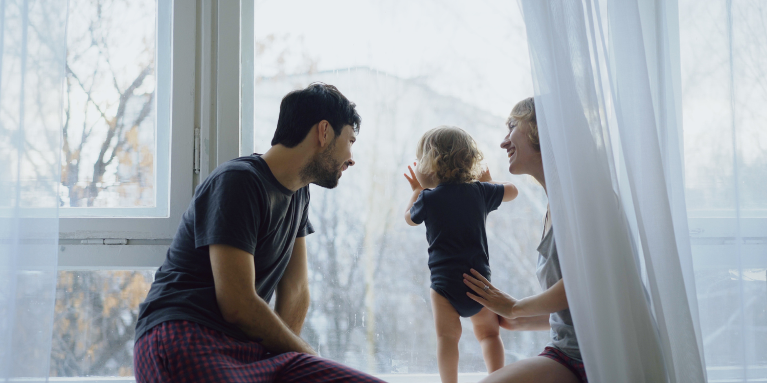 Family at home in Winter looking out the window with toddler - What to Look For When You’re Buying a Furnace