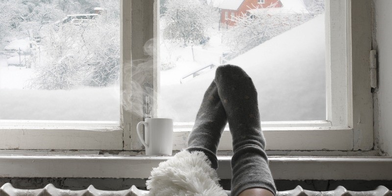 Women feet on heater with frosty window